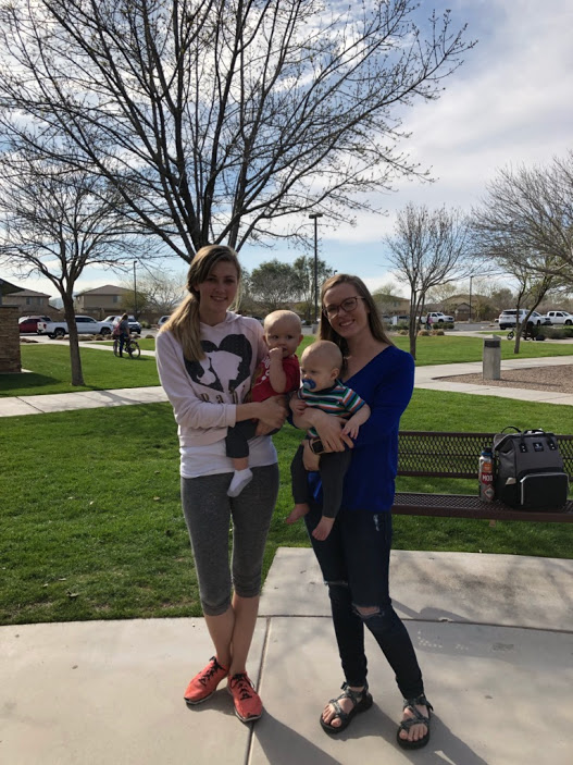 two women hold babies in park